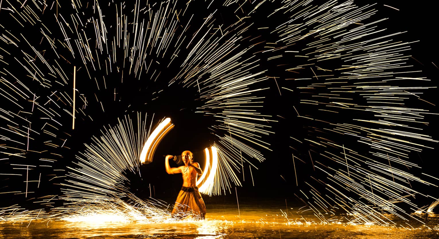 Streaks of light around man spinning fire