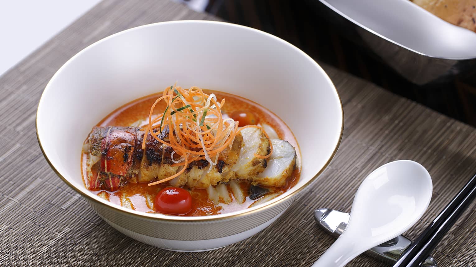 Bowl with lobster in red sauce, carrot garnish