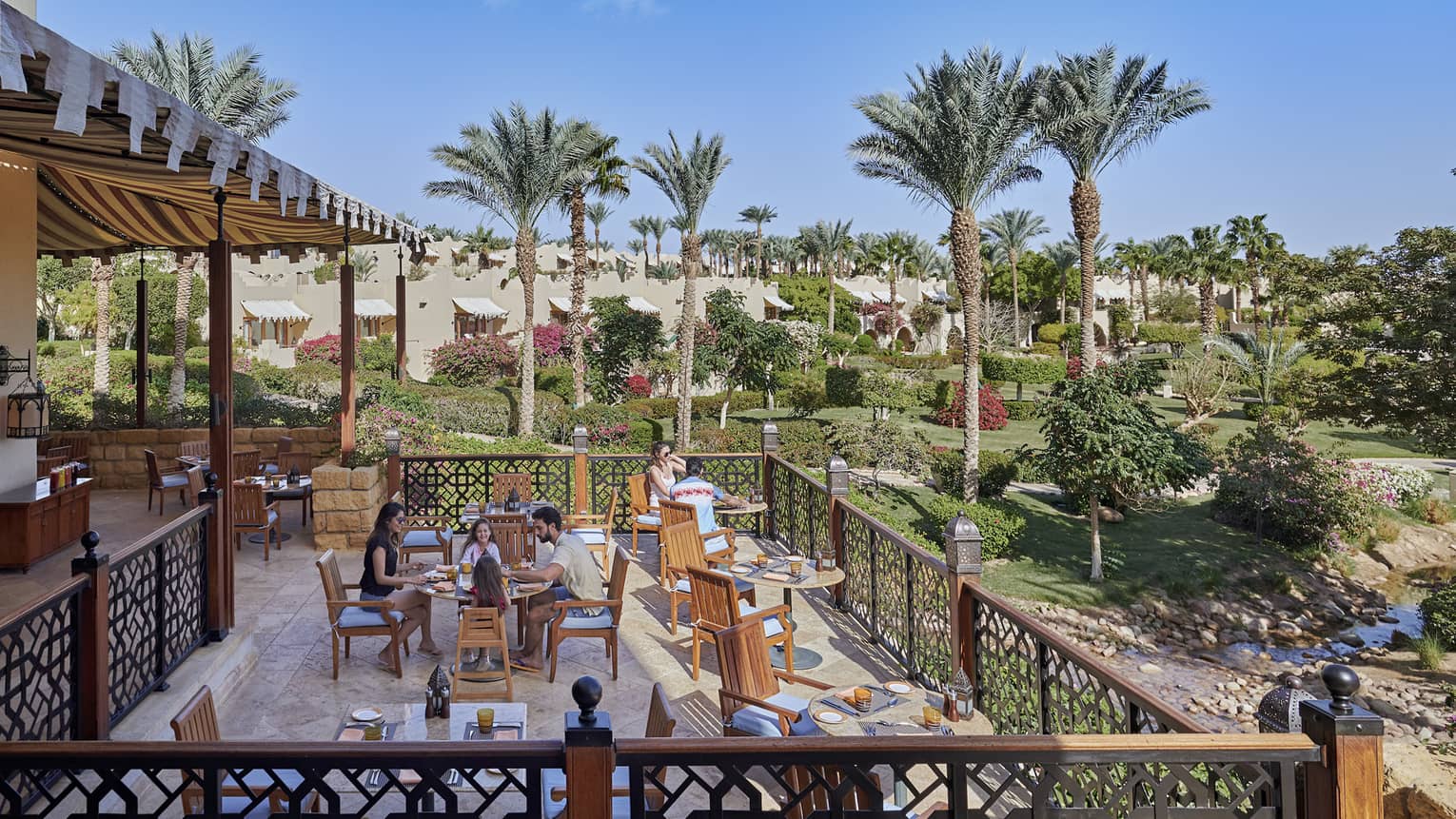 Outdoor restaurant on a wooden deck, overlooking palm trees