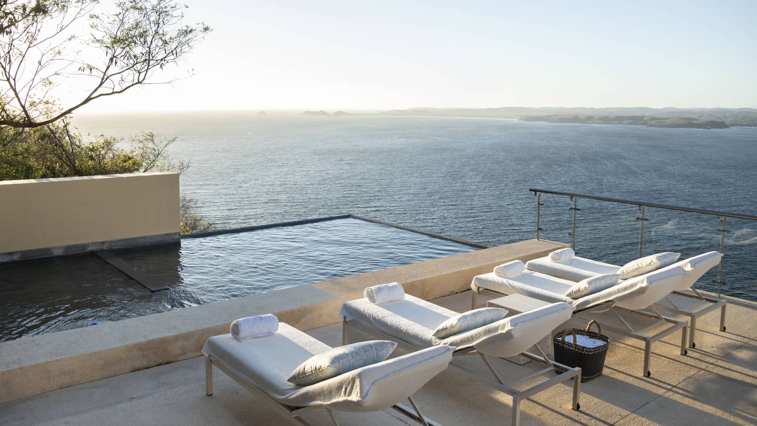 View of deck chairs, infinity pool and ocean beyond