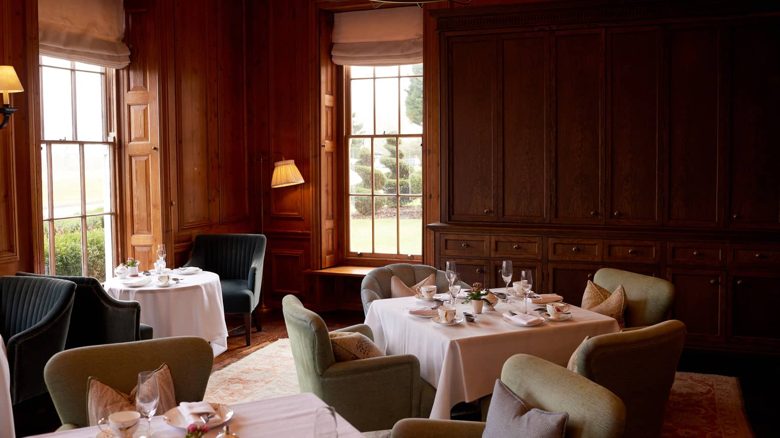 Cosy lounge with wood-panelled walls, small tables and chairs and dim lighting