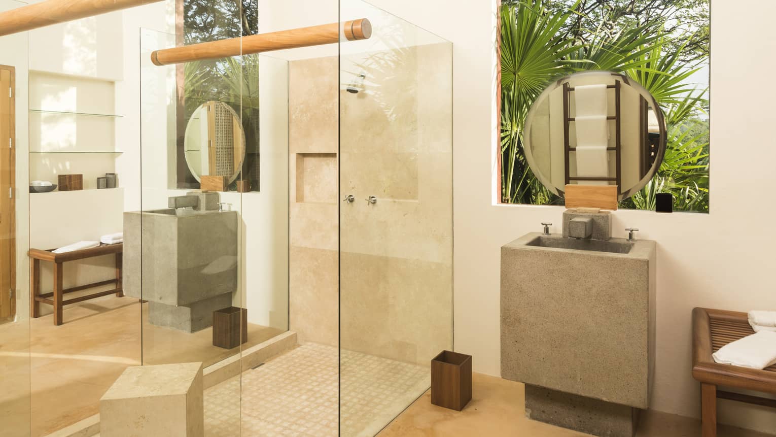 Contemporary bathroom with glass-walled shower, concrete sink and opening to tropical trees