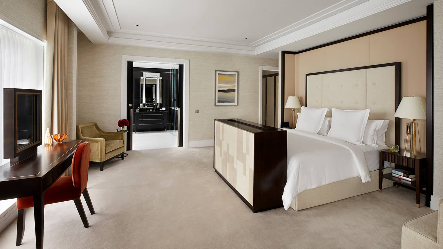 Bed against padded headboard, wall across from desk and TV, window