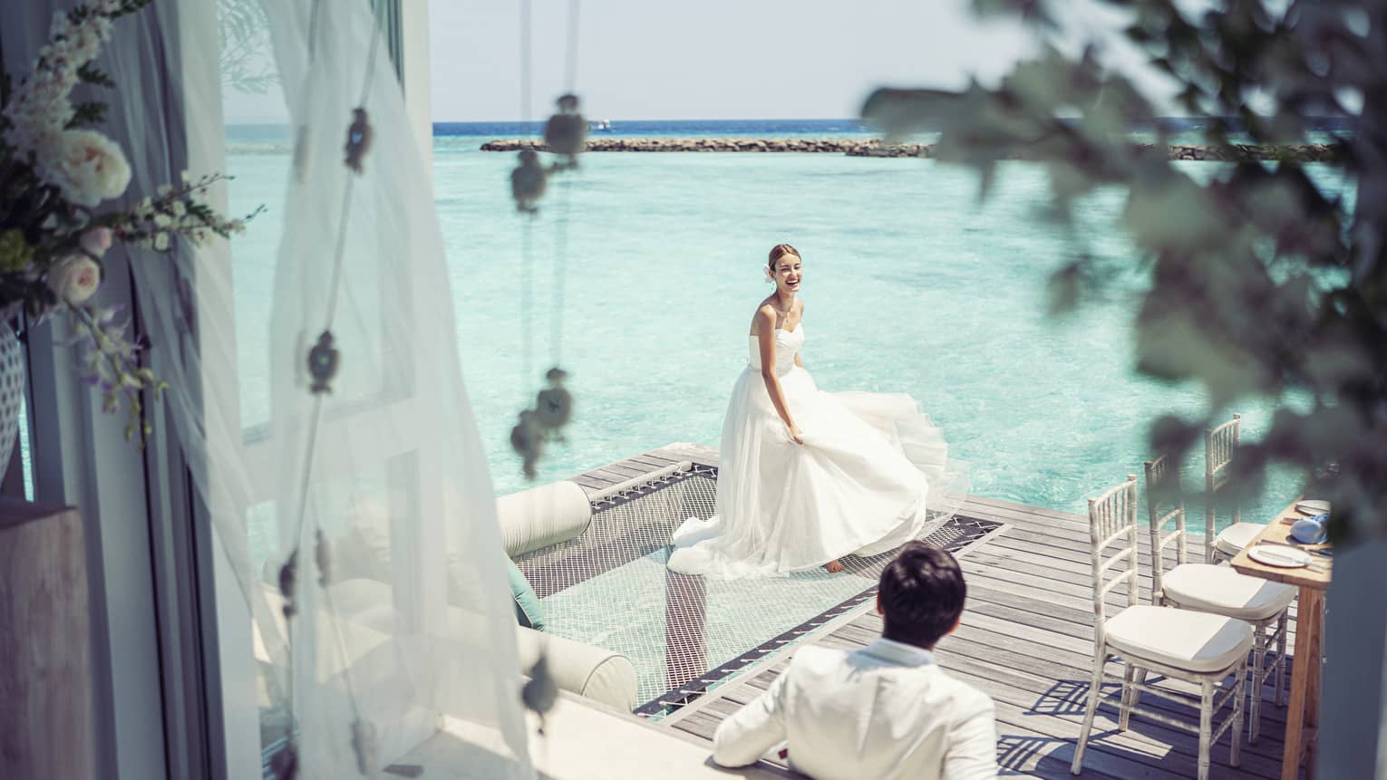 Bride and groom relax before their reception in their overwater wedding bungalow with glass-bottom floor