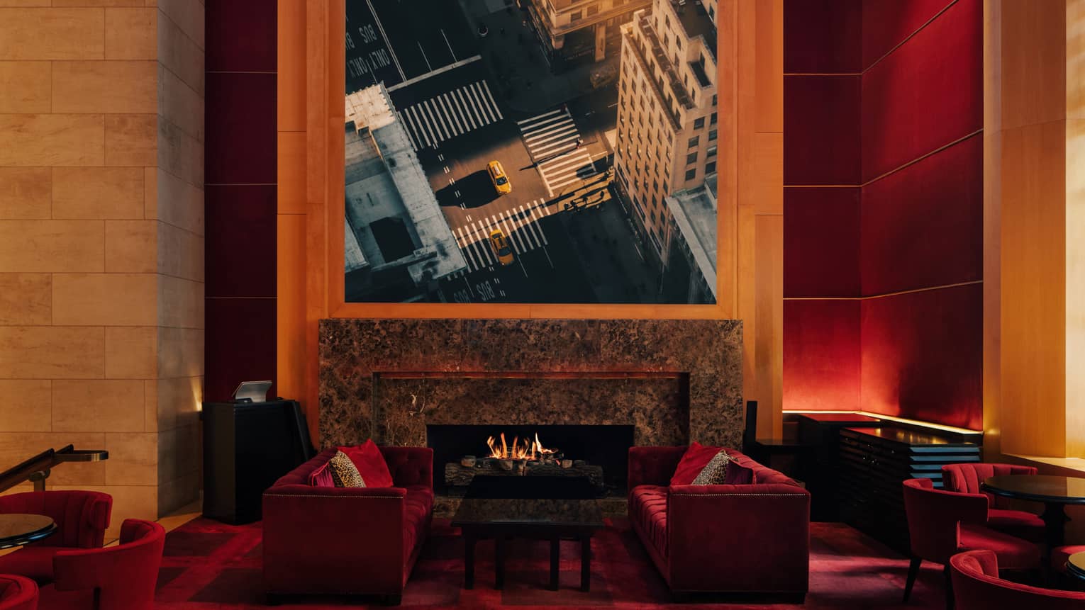 A cozy lounge space with upholstered seating, artistic decor, high ceilings and a fireplace
