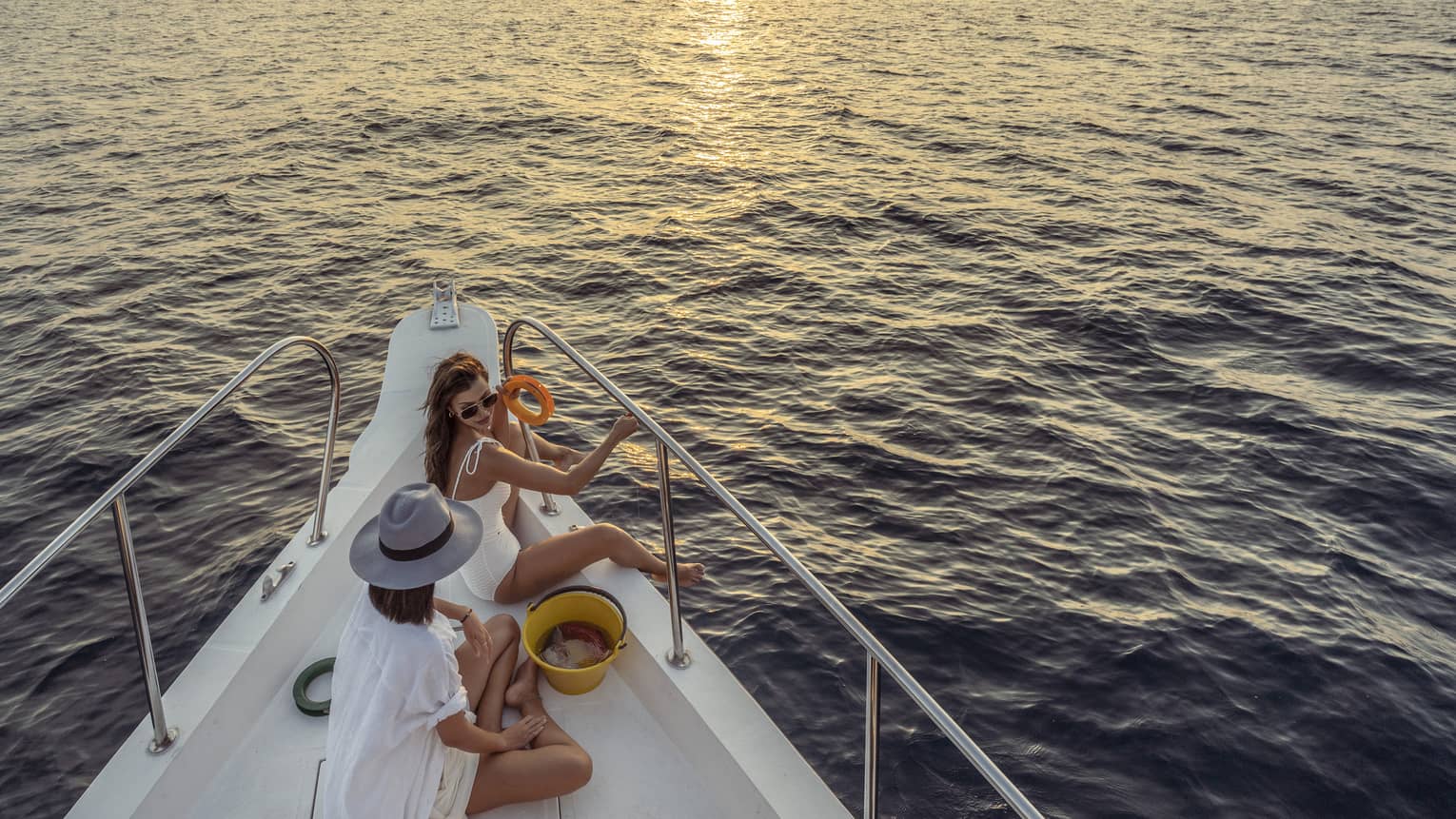 Two women enjoy snacks at the helm of a private yacht at sunset