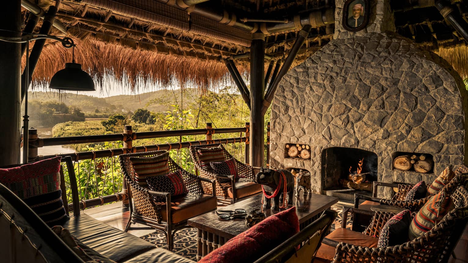 Burma Bar bamboo armchairs, sofa around table in front of stone fireplace