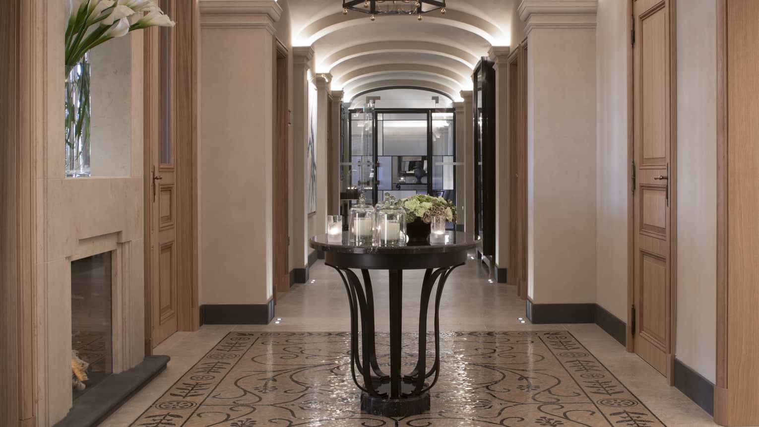 Hotel hallway with marble floors, round table with multiple white candles in glass votives, fresh flowers