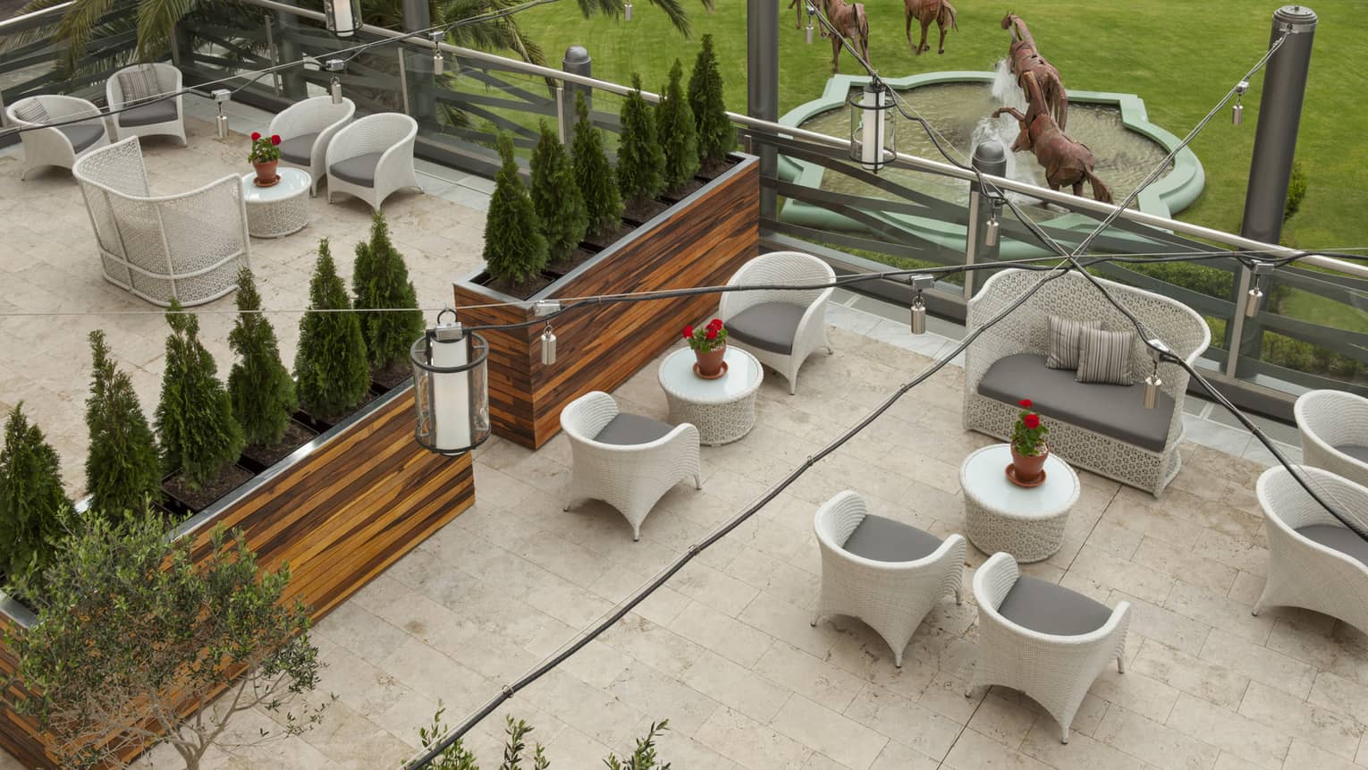 Aerial view of Arrabal garden terrace with white patio sofa and cocktail tables, row of hedges