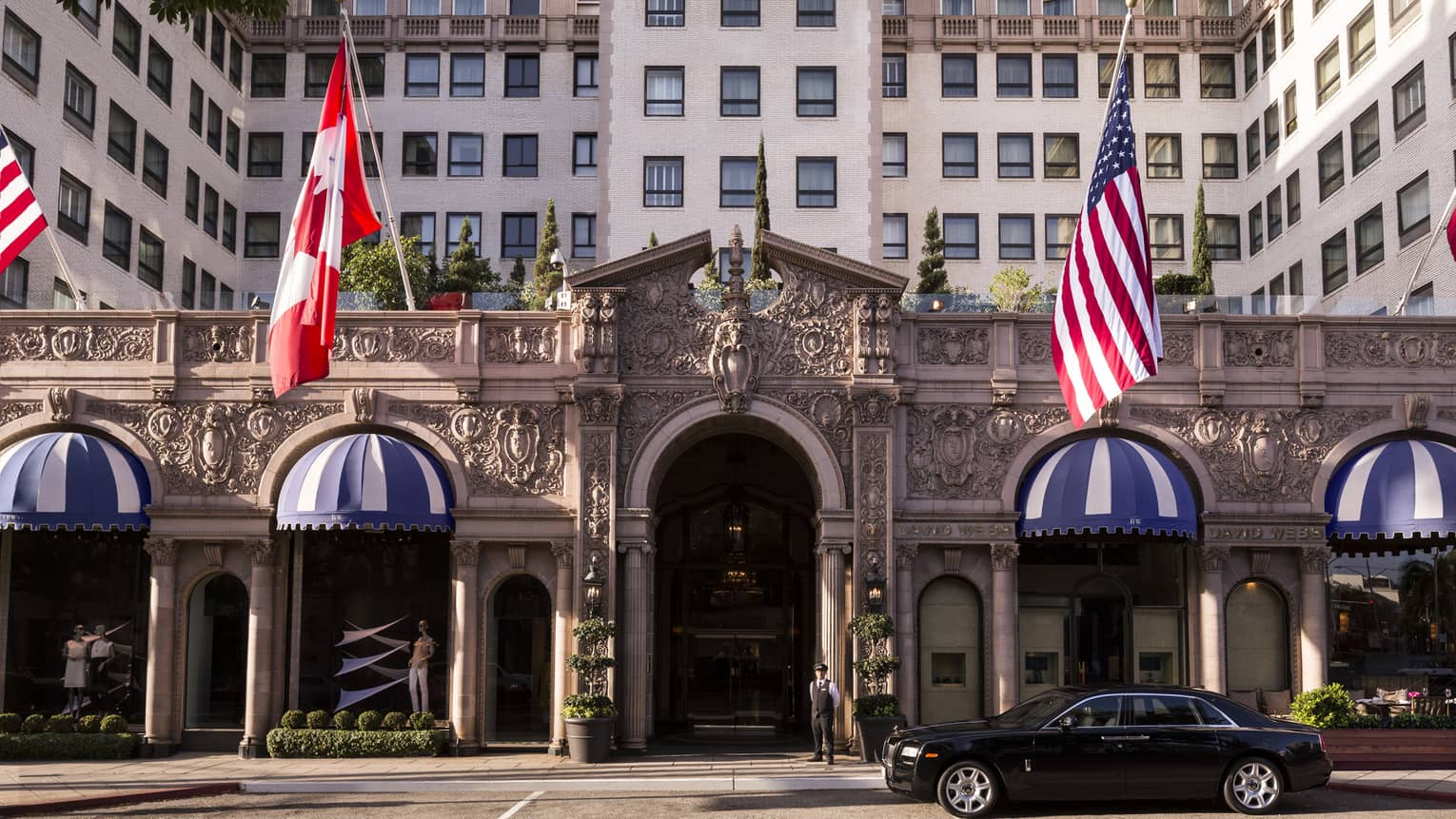 Outside of a building with a car in front and flags.