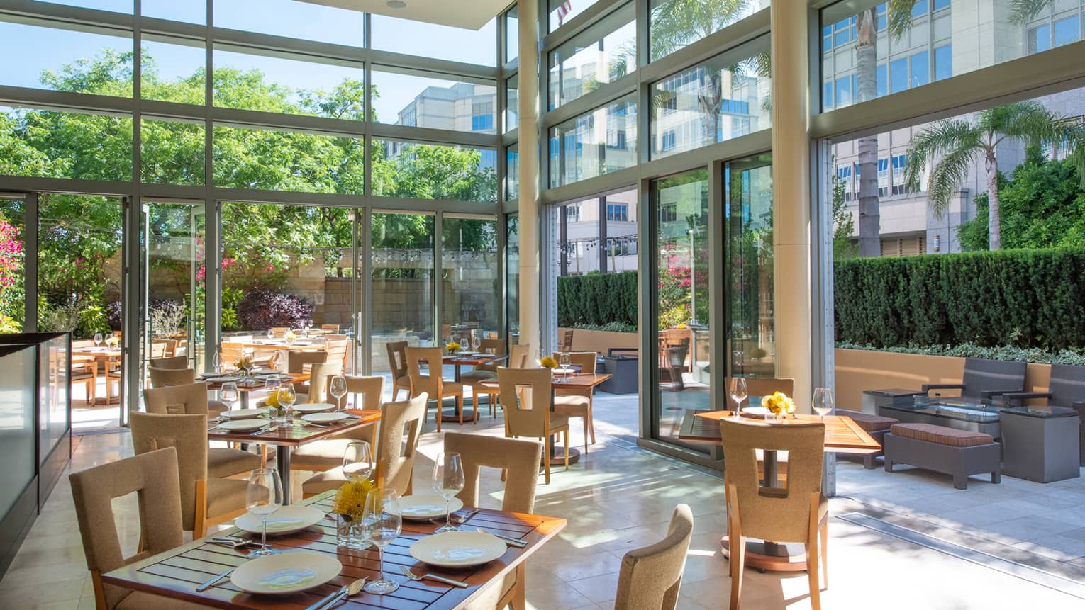 A restaurant with sun coming in through large glass windows and walls.