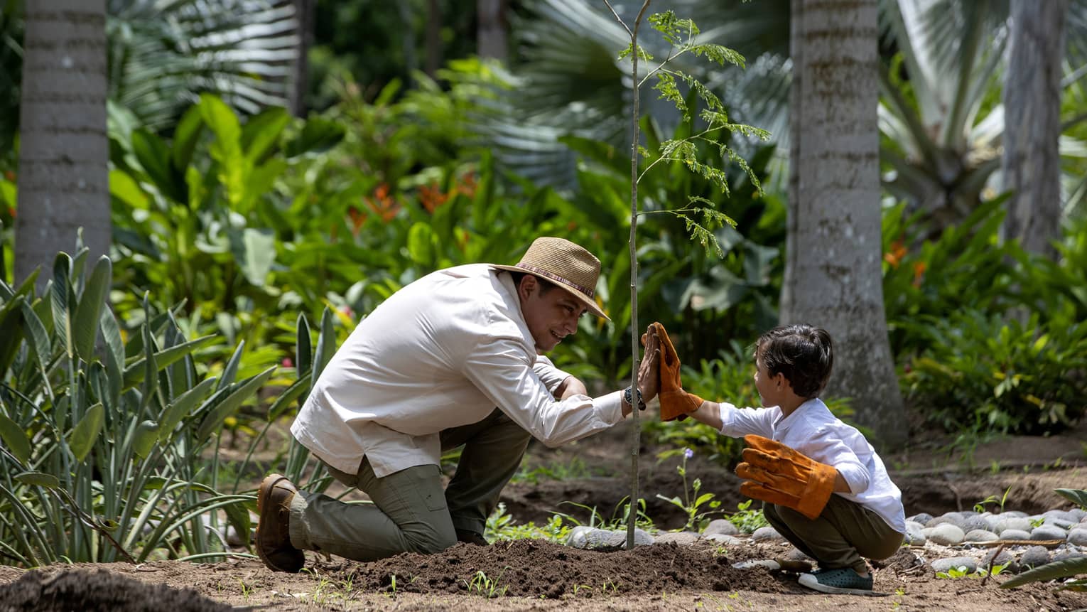 Two guests giving each other a high five while wearing gloves surrounded by nature.