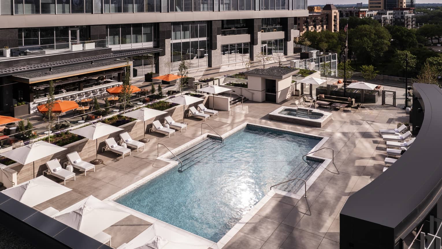 An outdoor pool surrounded by lounge chairs and large umbrellas.