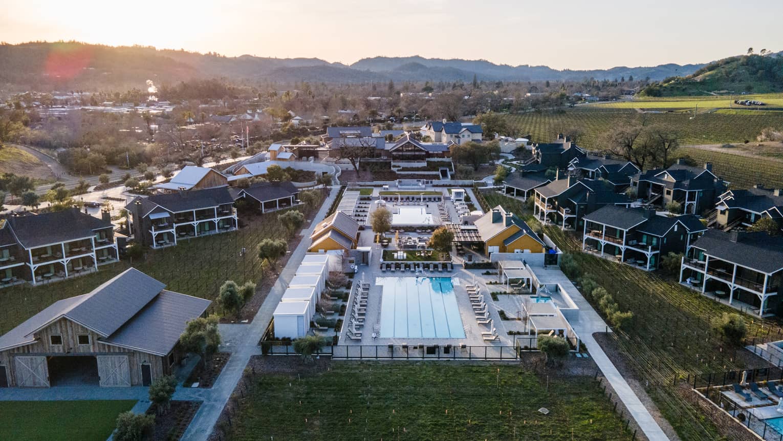 Aerial view of residences, land, trees and a pool.