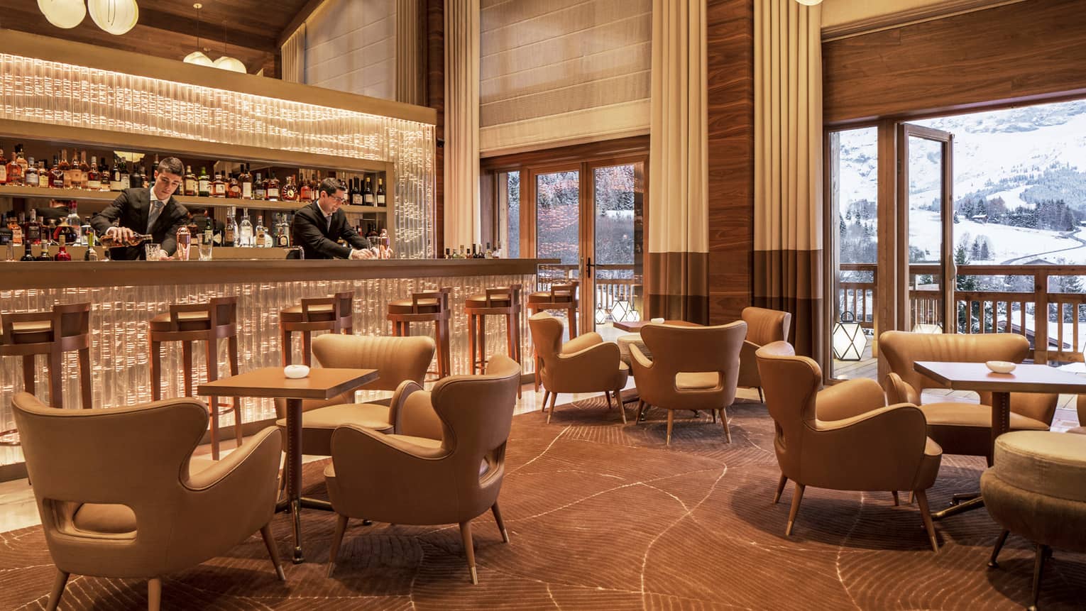 Bartenders mix drinks at Le 1920 bar by midcentury-style lounge chairs, tables, under soaring ceilings