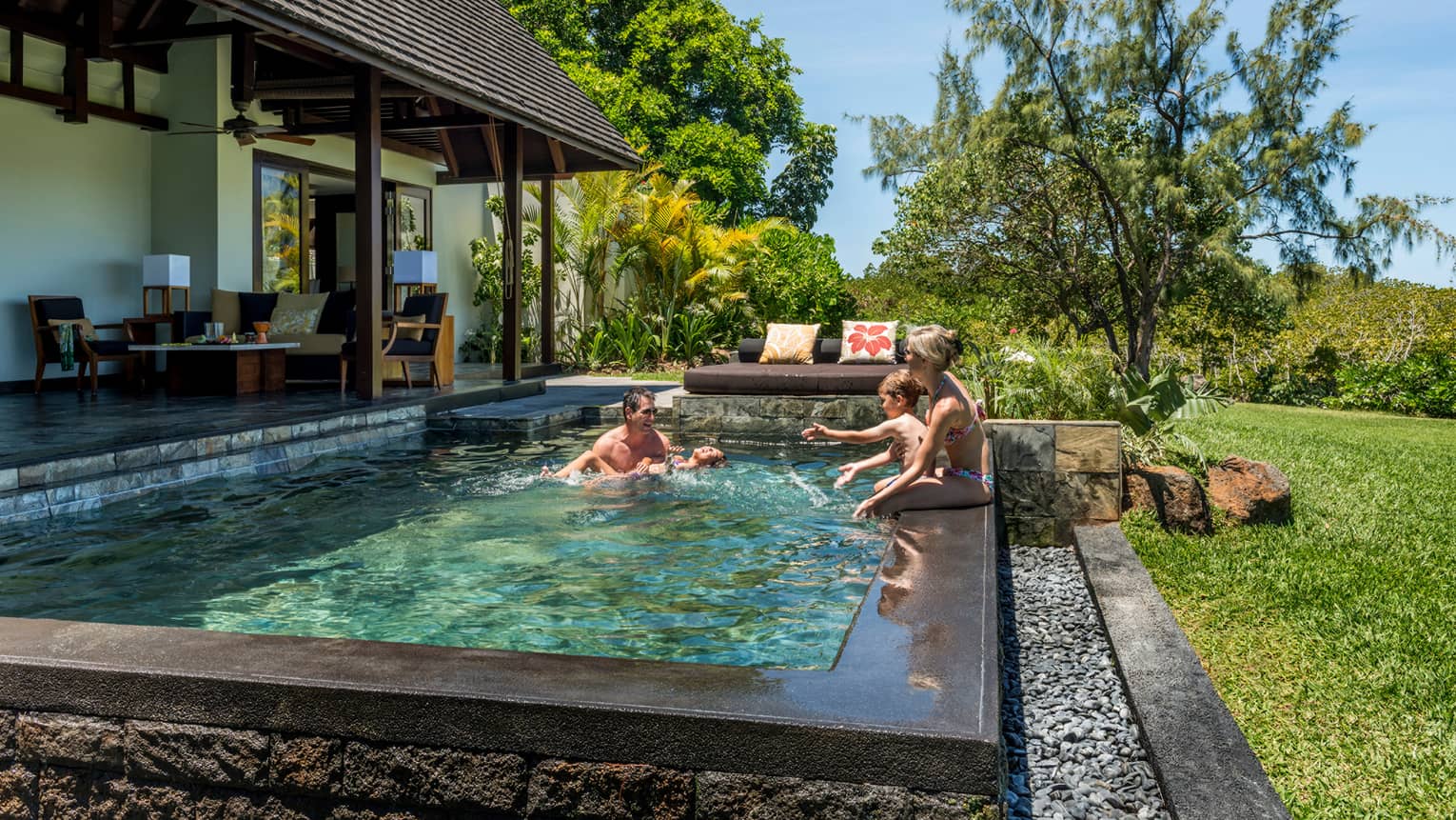 Couple, two children laugh, splash in sunny Garden Villa plunge swimming pool