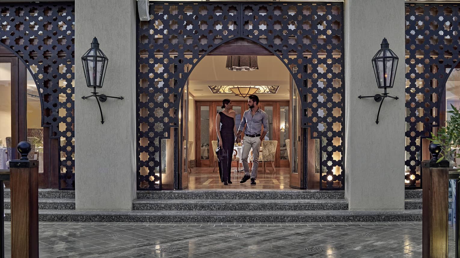 Man and woman walking out of a restaurant with Arabesque detailing around doorway