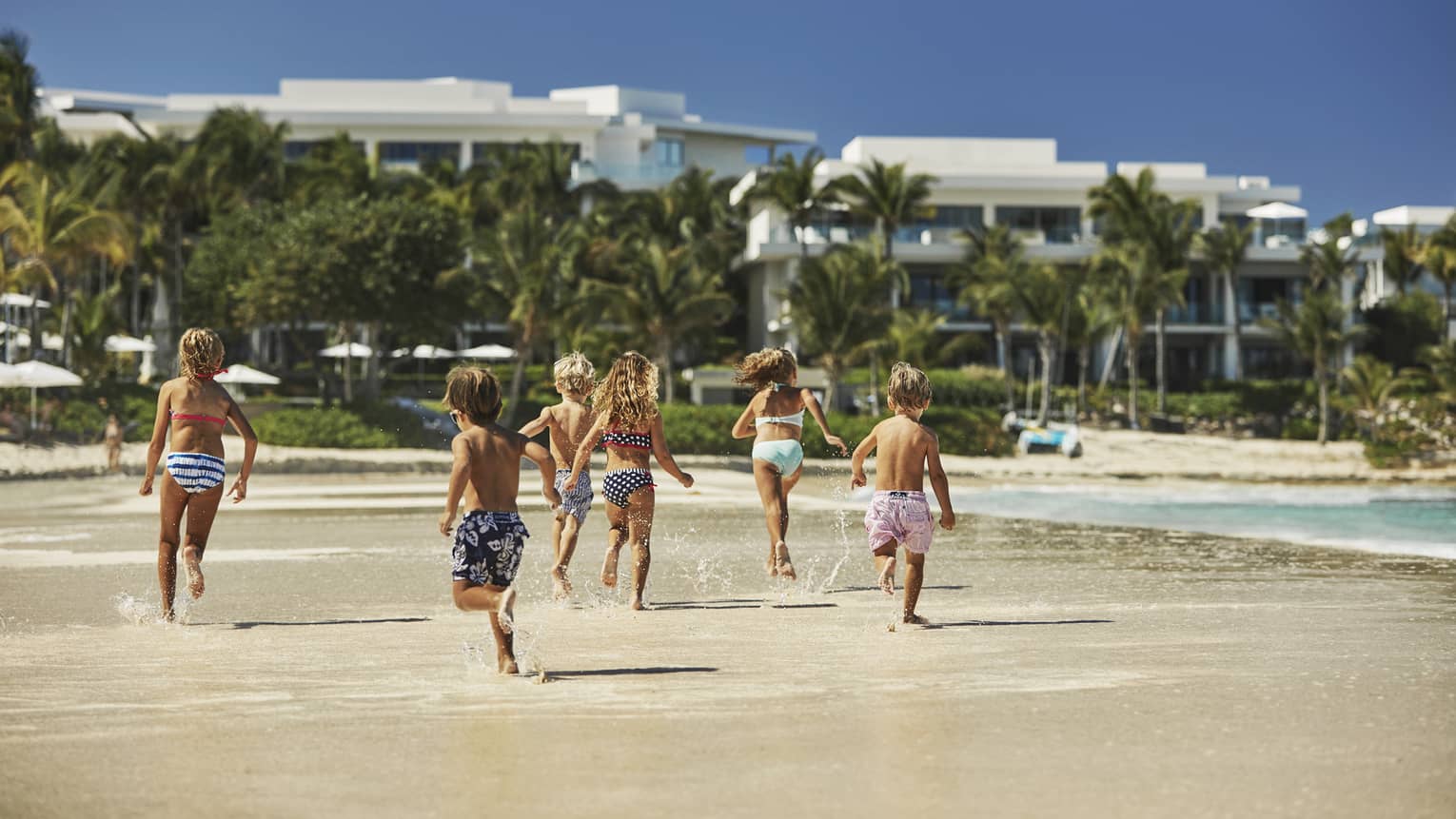 A group of children running on a beach.