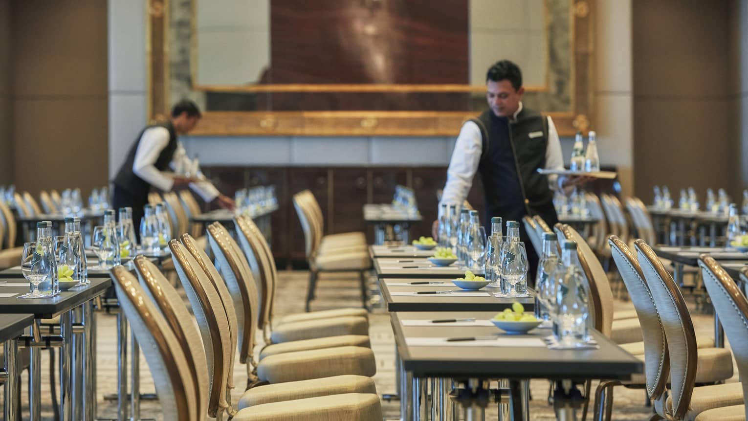 Conference in ballroom, hotel staff set rows of meeting tables and chairs  