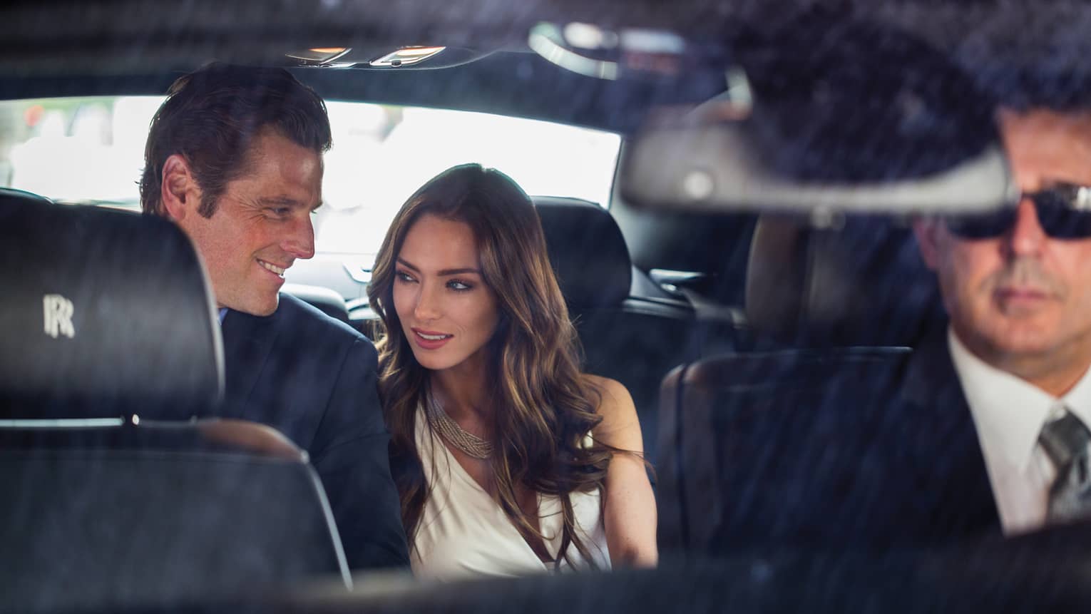 Man and woman in the back seat of a Rolls Royce house car