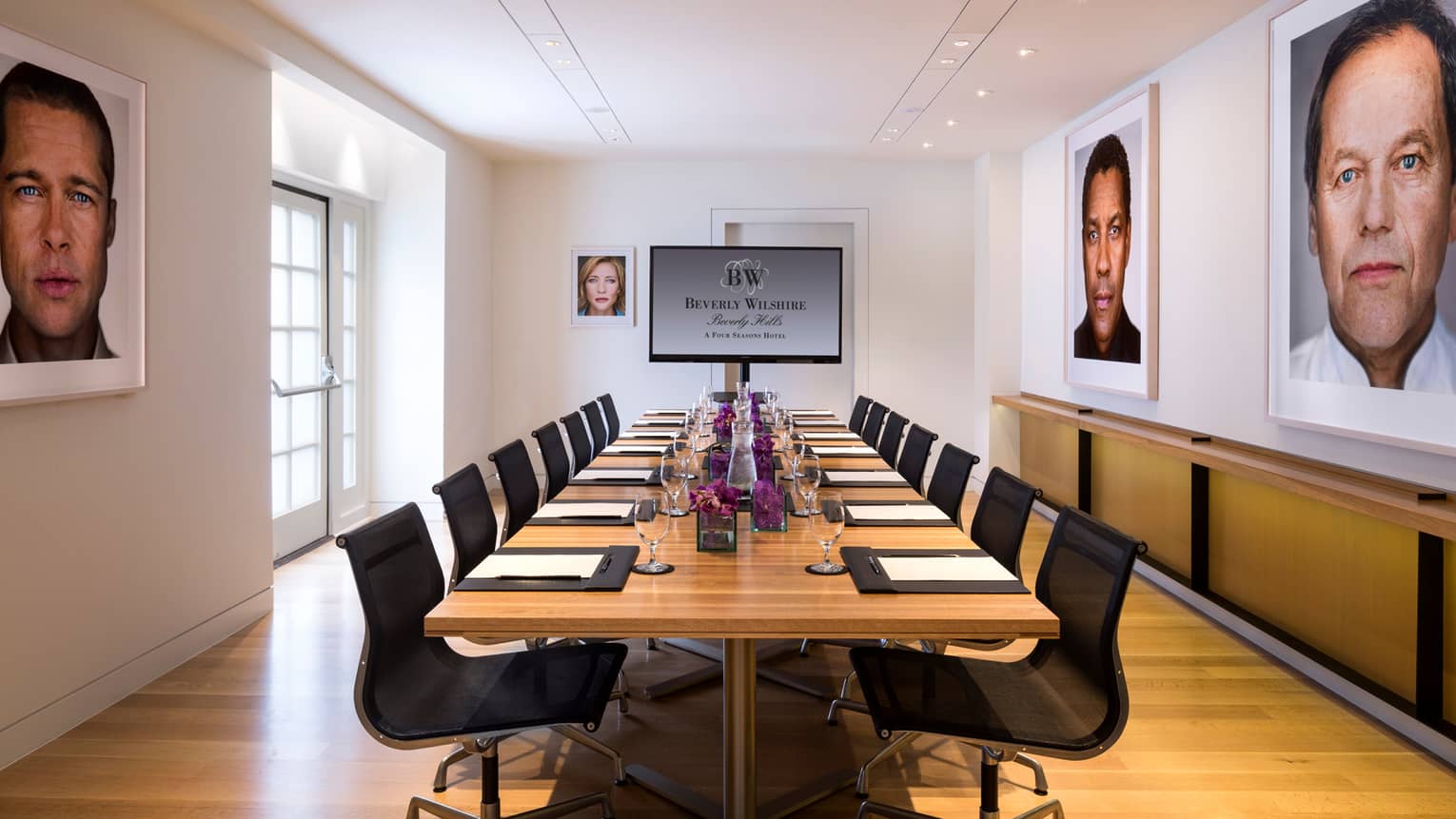 Petit Cut long meeting table, TV screen at end, framed prints of Hollywood stars