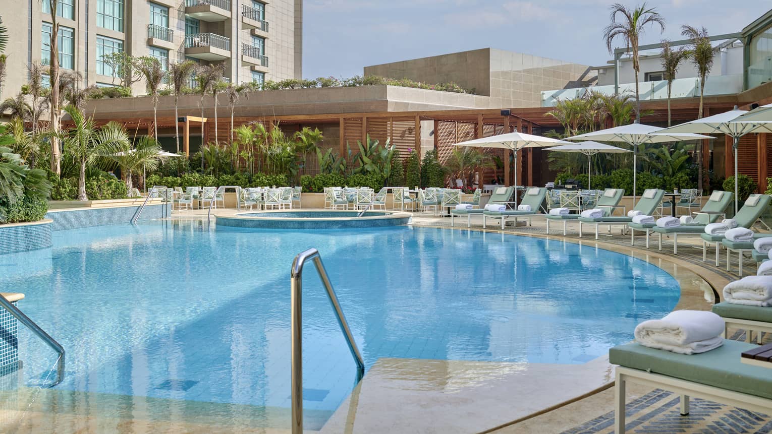 Outdoor pool with lounge chairs lining the edge, umbrellas, foliage