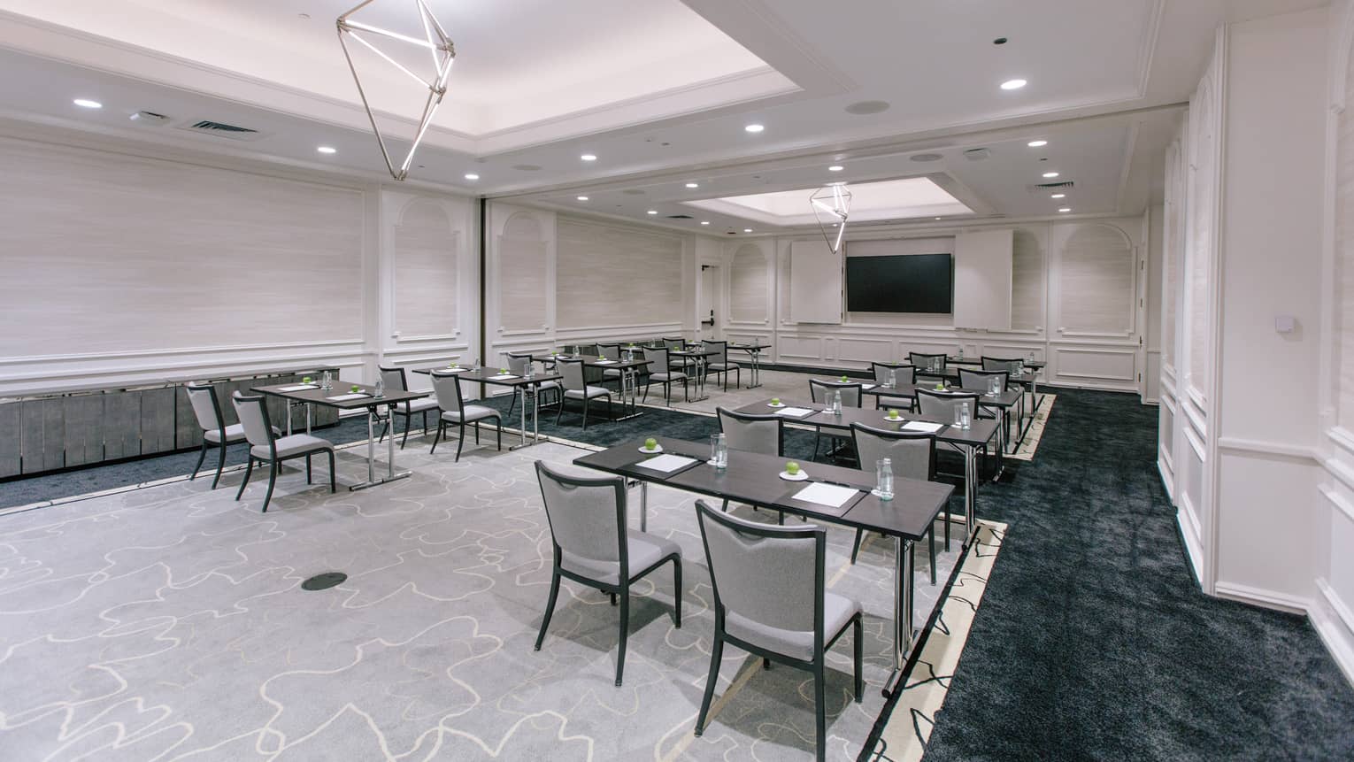 A large meeting room with desks and chairs in rows.