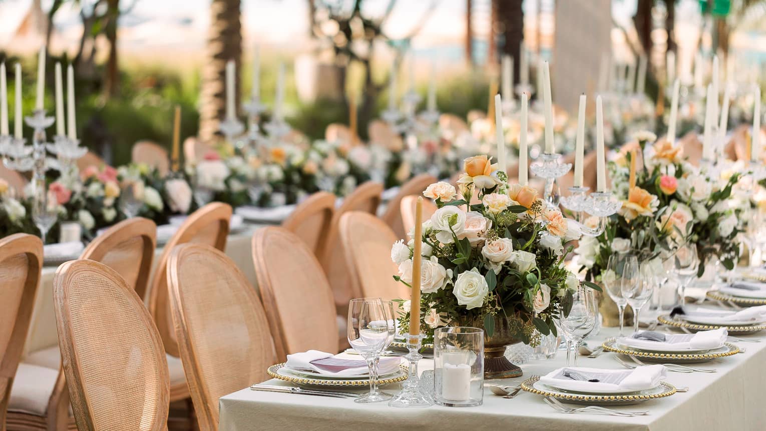 Banquet dining tables with pink chairs, floral displays at outdoor garden wedding reception