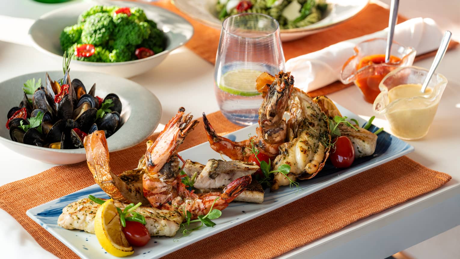 Grilled seafood platter with cod, seabass, shrimp and lobster served on a blue-and-white rectangular plate