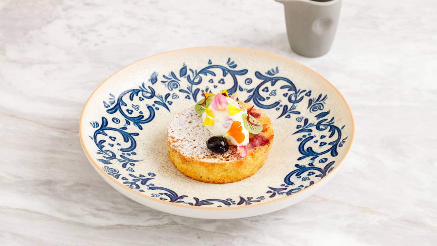 Cherry and almond cake round topped with floral garnish and ice cream