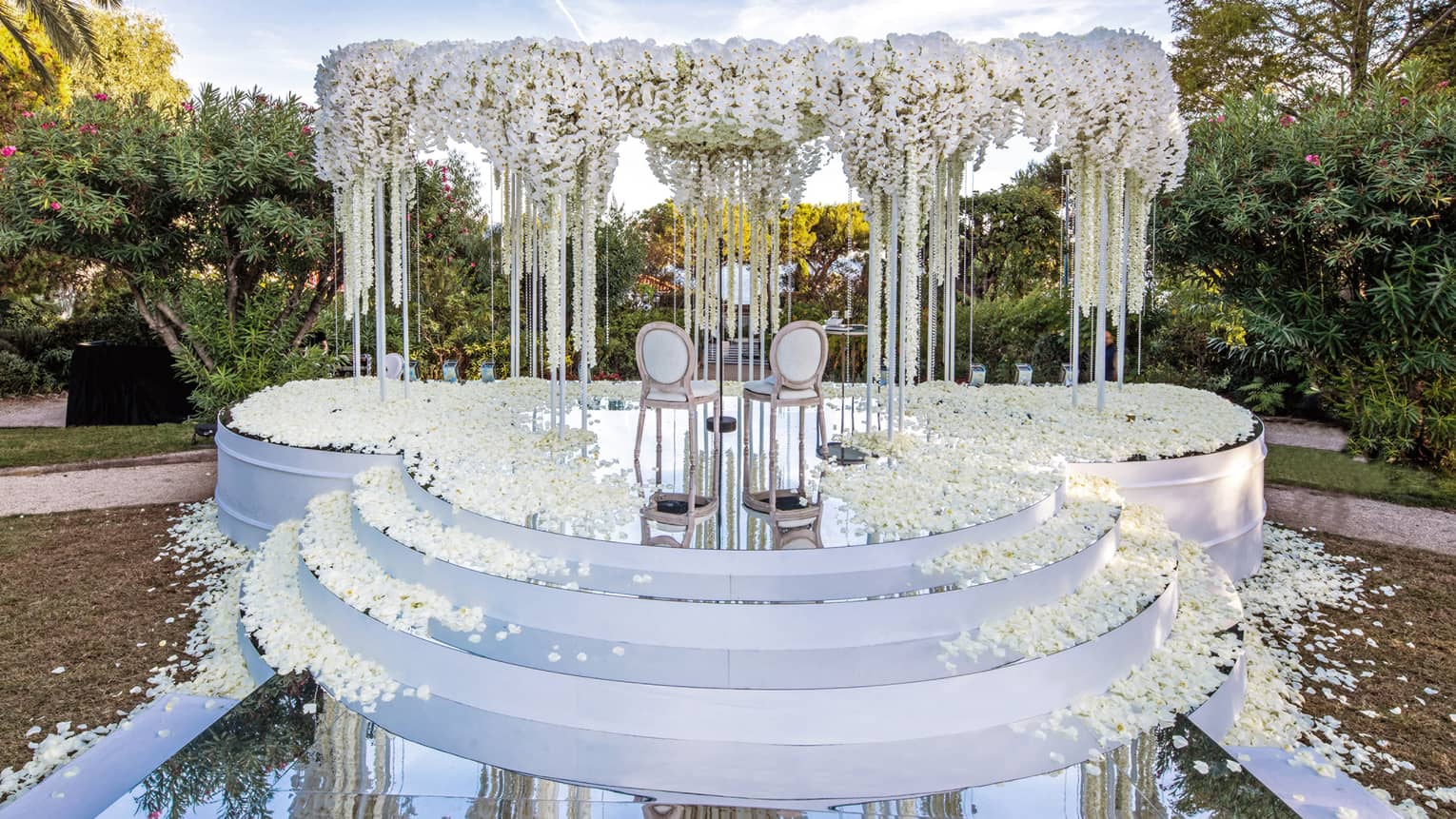 Three rounded white steps leading up to altar with arch covered in white flowers