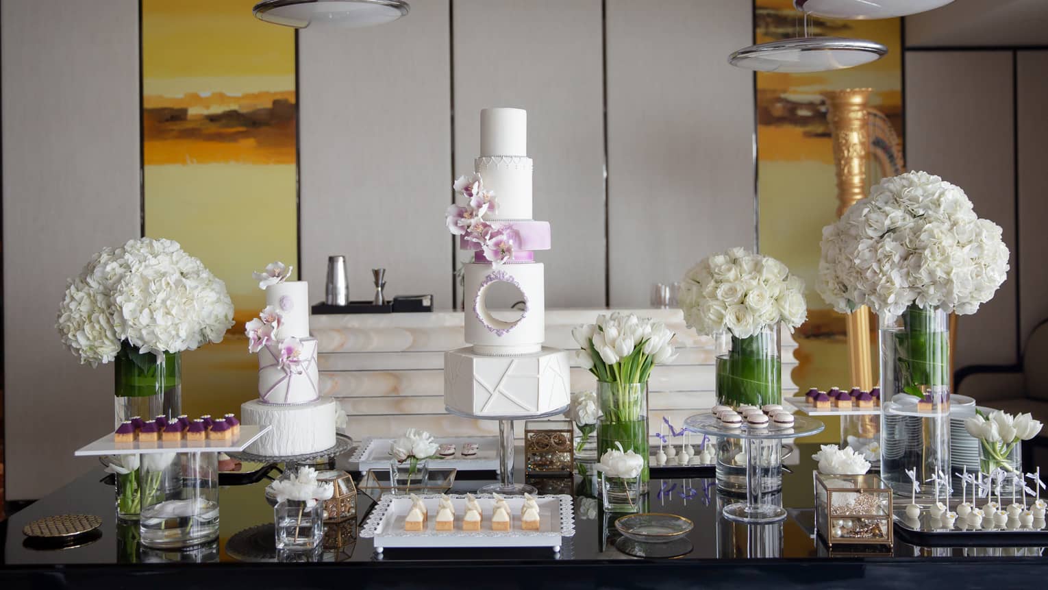 Wedding cake and dessert display with white roses in vases
