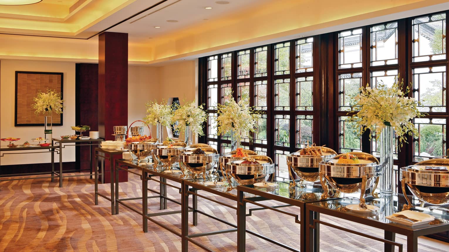 Long dining buffet with steel food stations, flowers in vases
