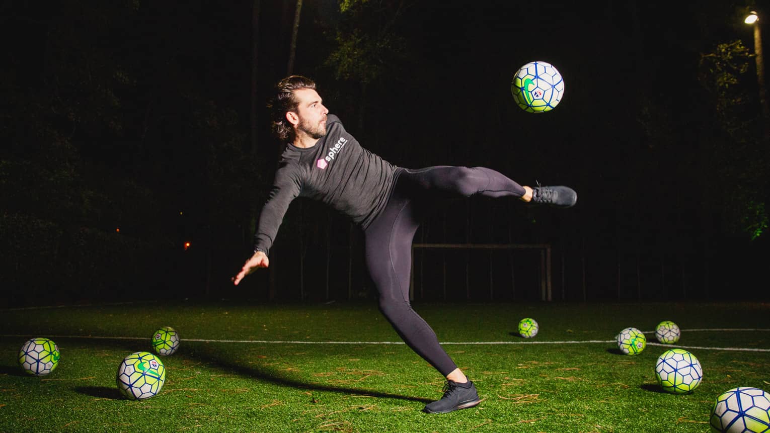POWA by sphere session, Michael Chabala kicks soccer ball in mid-air on field with multiple balls at night