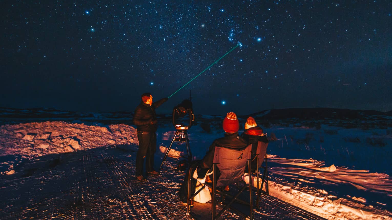 An instructor uses a laser pointer as he identifies constellations for guests