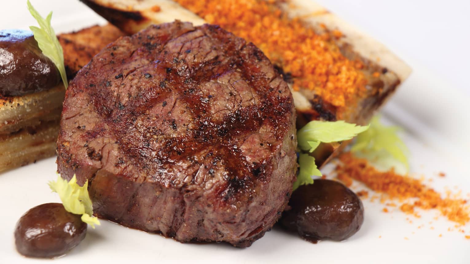 Grilled 12-ounce American Wagyu New York Strip steak on plate with black olives, lettuce