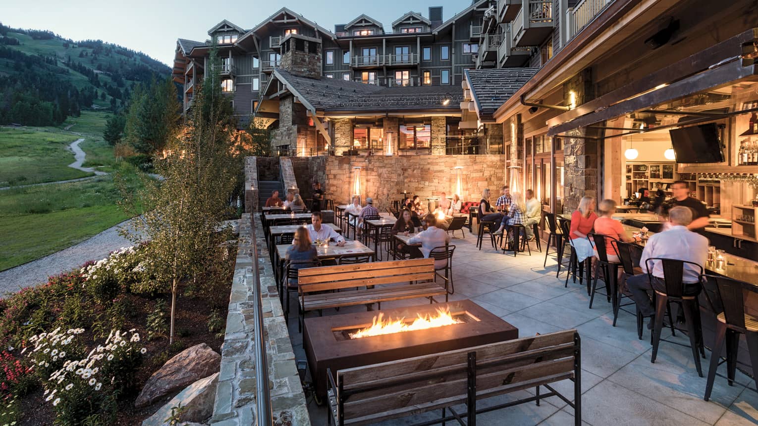 Outdoor patio of Handle Bar restaurant/pub with firepit, tables and bar seating with mountain view