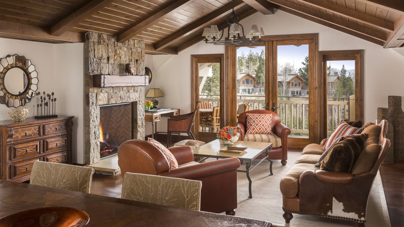 Penthouse Resort living room oversized leather chairs, cowhide sofa, stone fireplace, wood trim patio doors