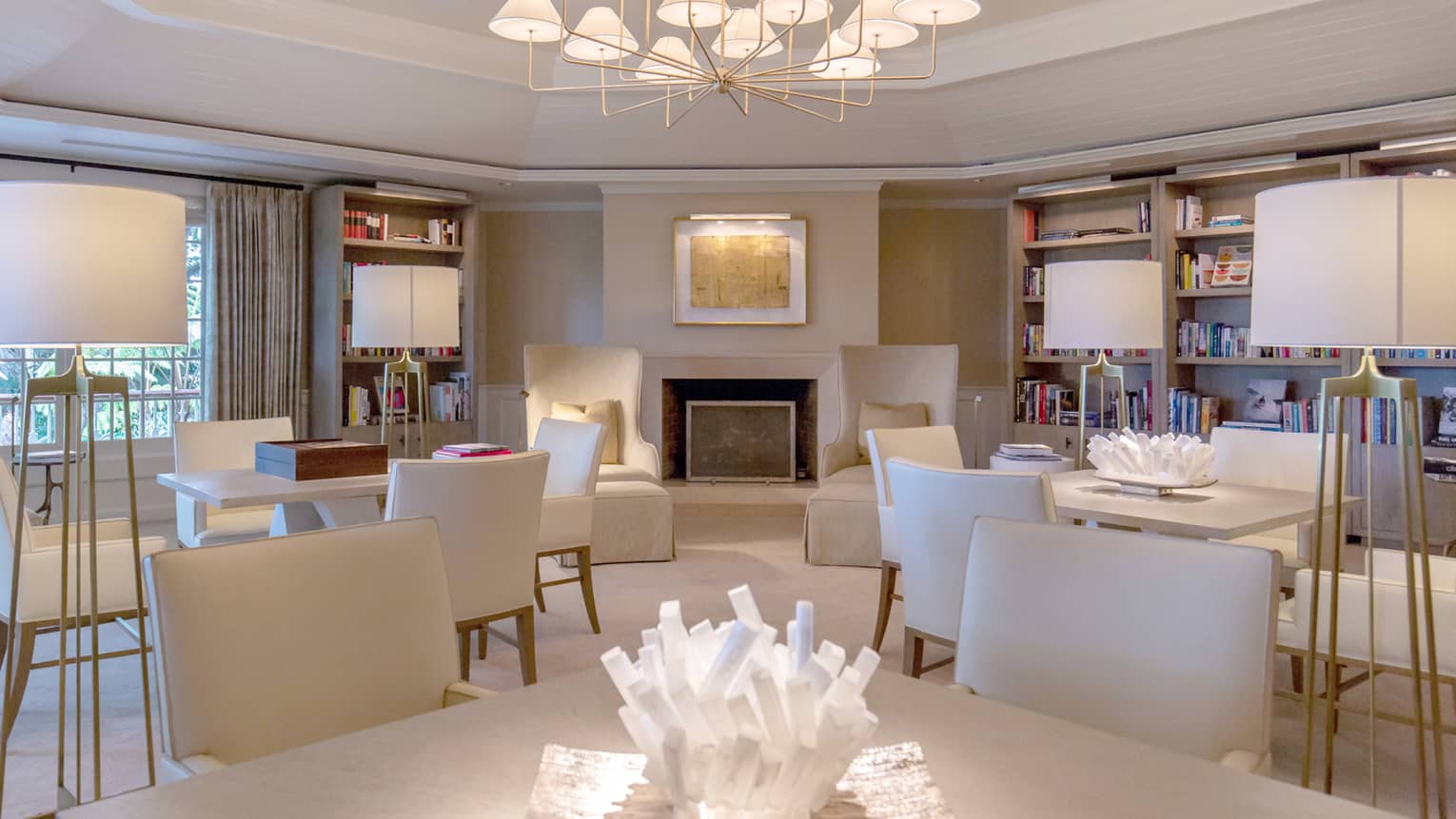 A brightly lit library with many tables and chairs and bookshelves lining the walls.