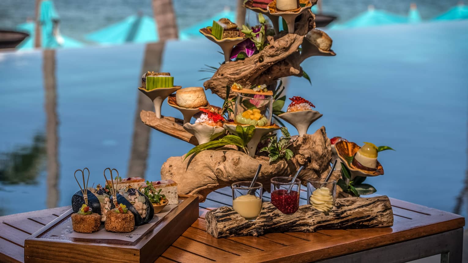 Afternoon tea spread with sweets and savouries presented on a piece of driftwood