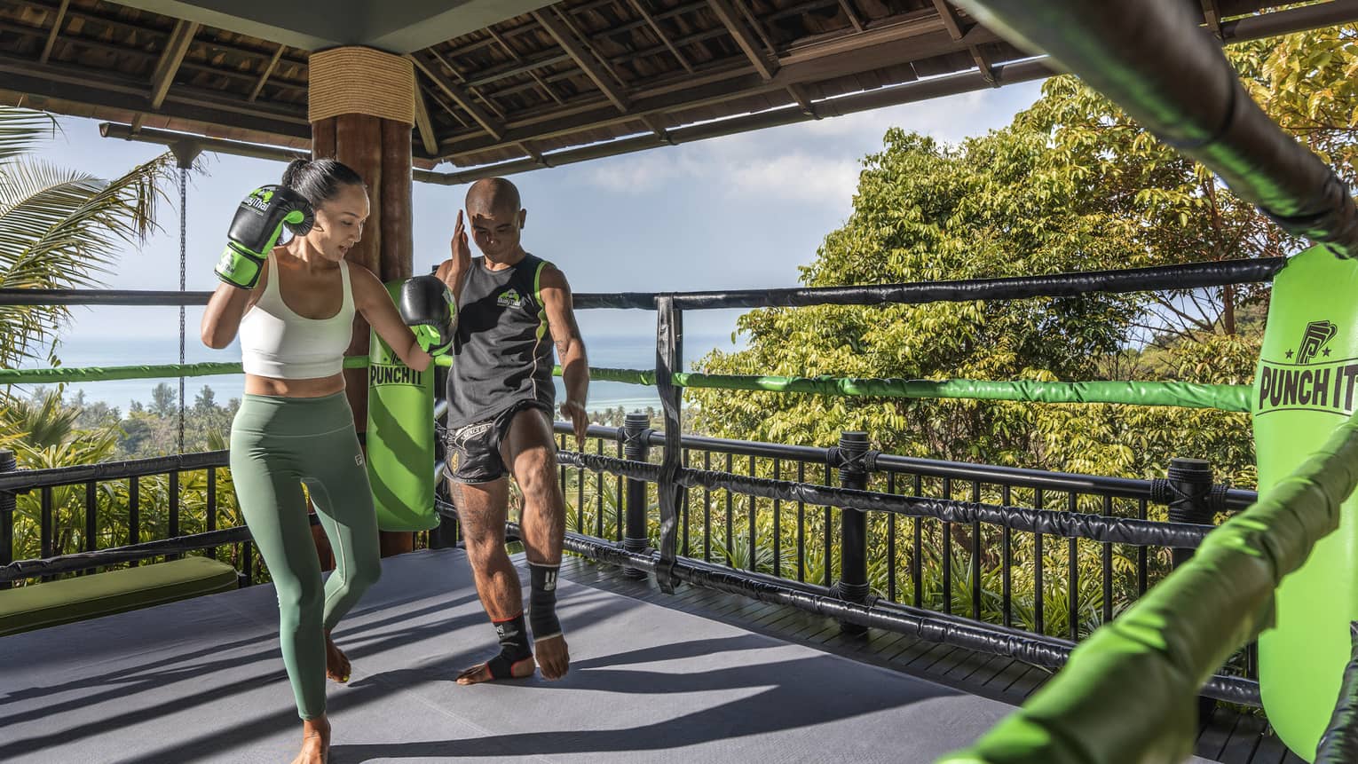 Muay Thai trainer teaches woman in outdoor ring