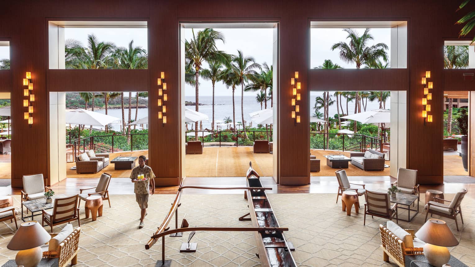 Server carries tray with cocktails through large Malibu Farm Bar dining room