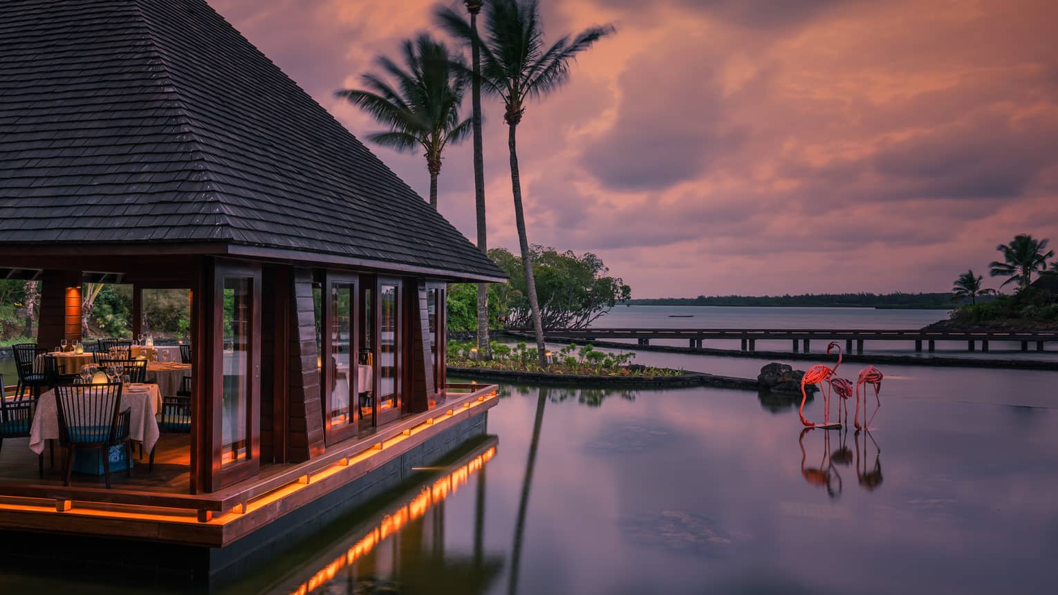 Beau Champ restaurant pavilion at sunset, two pink flamingo sculptures in water