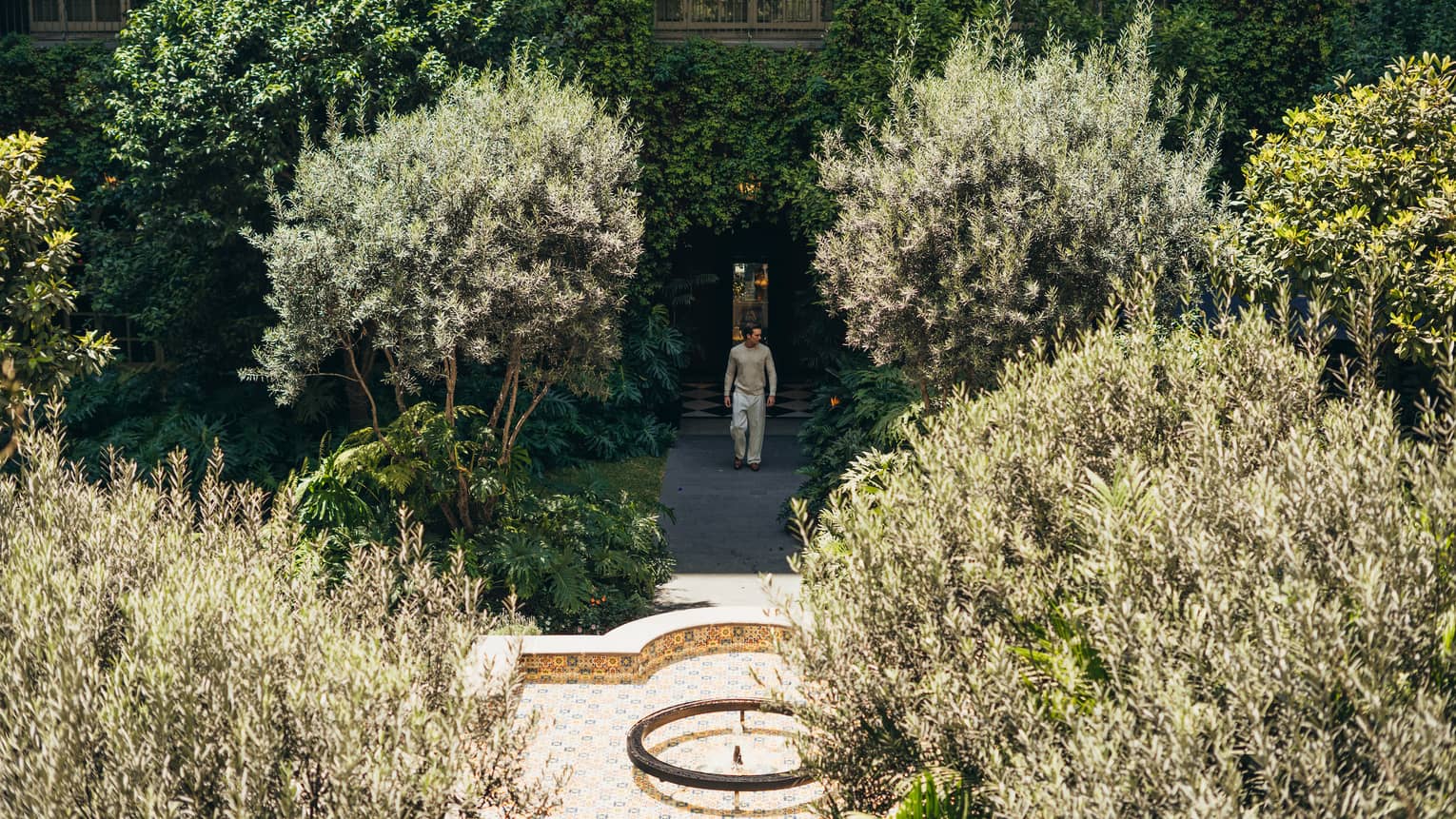 A guest walks out of the hotel into a tree-filled courtyard