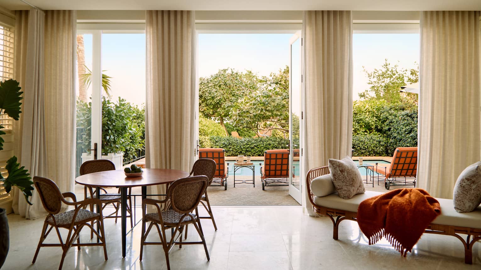 Dining table for four and chaise in a great room that leads out to a private pool