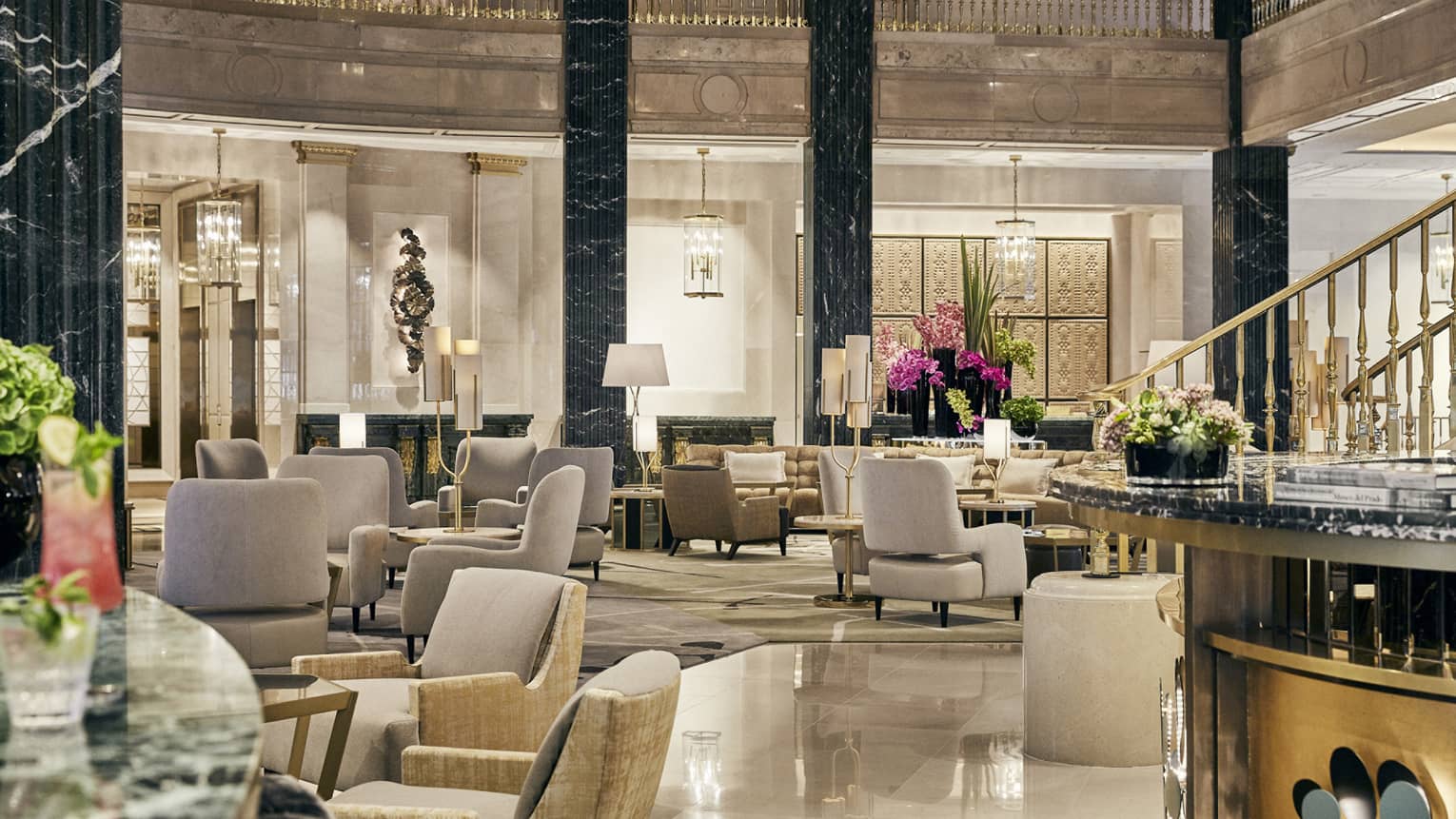 2-story columned lobby with marble flooring, gold accents and leather chairs