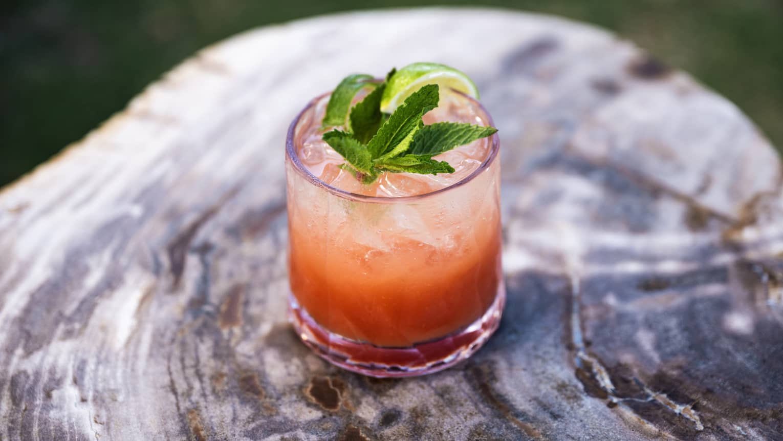 Orange beverage with lime and greens on top.