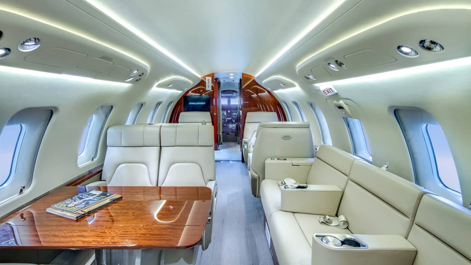 Interior of private jet, with white leather seats and wooden table