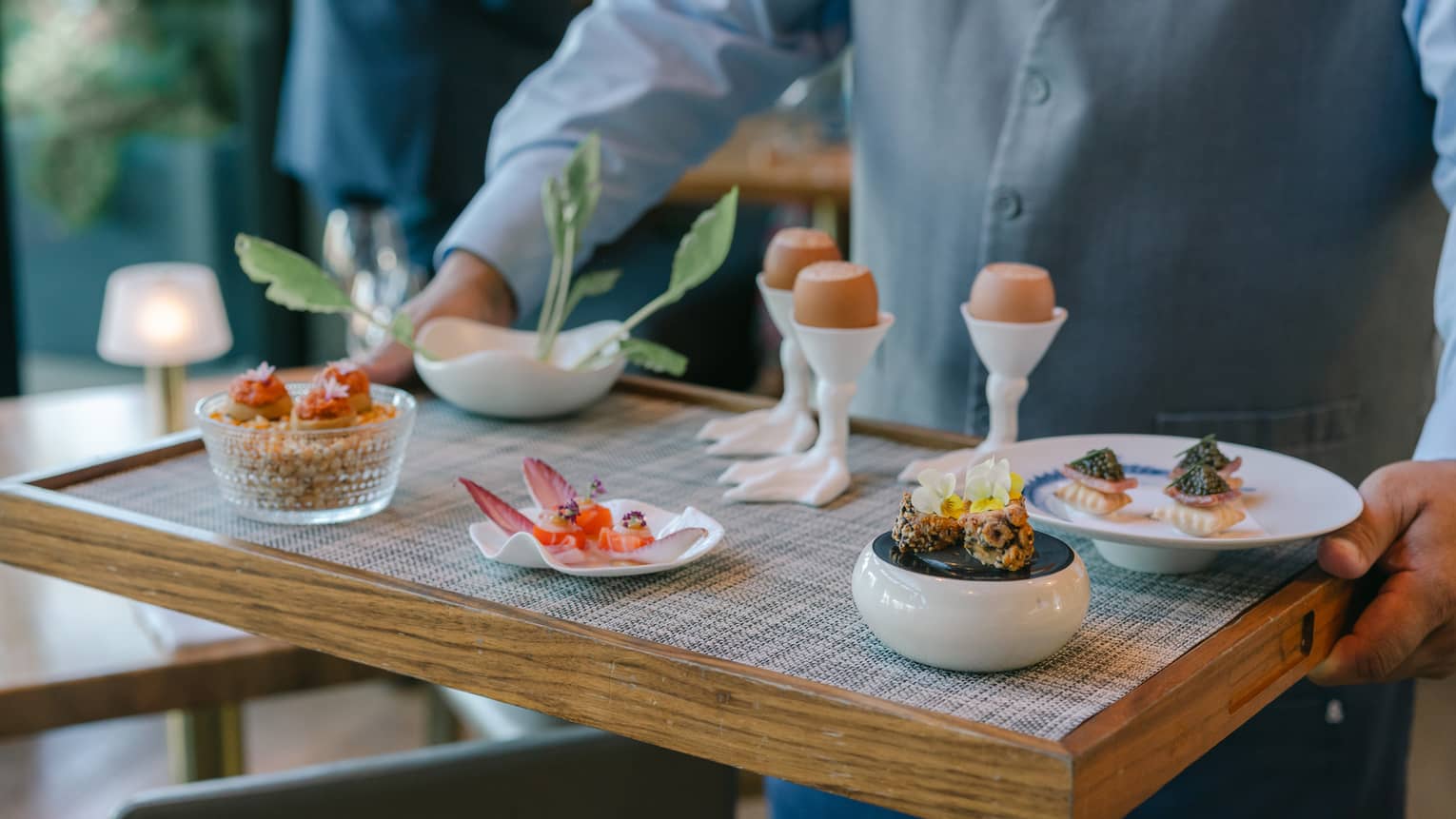 A person holding a tray of culinary dishes
