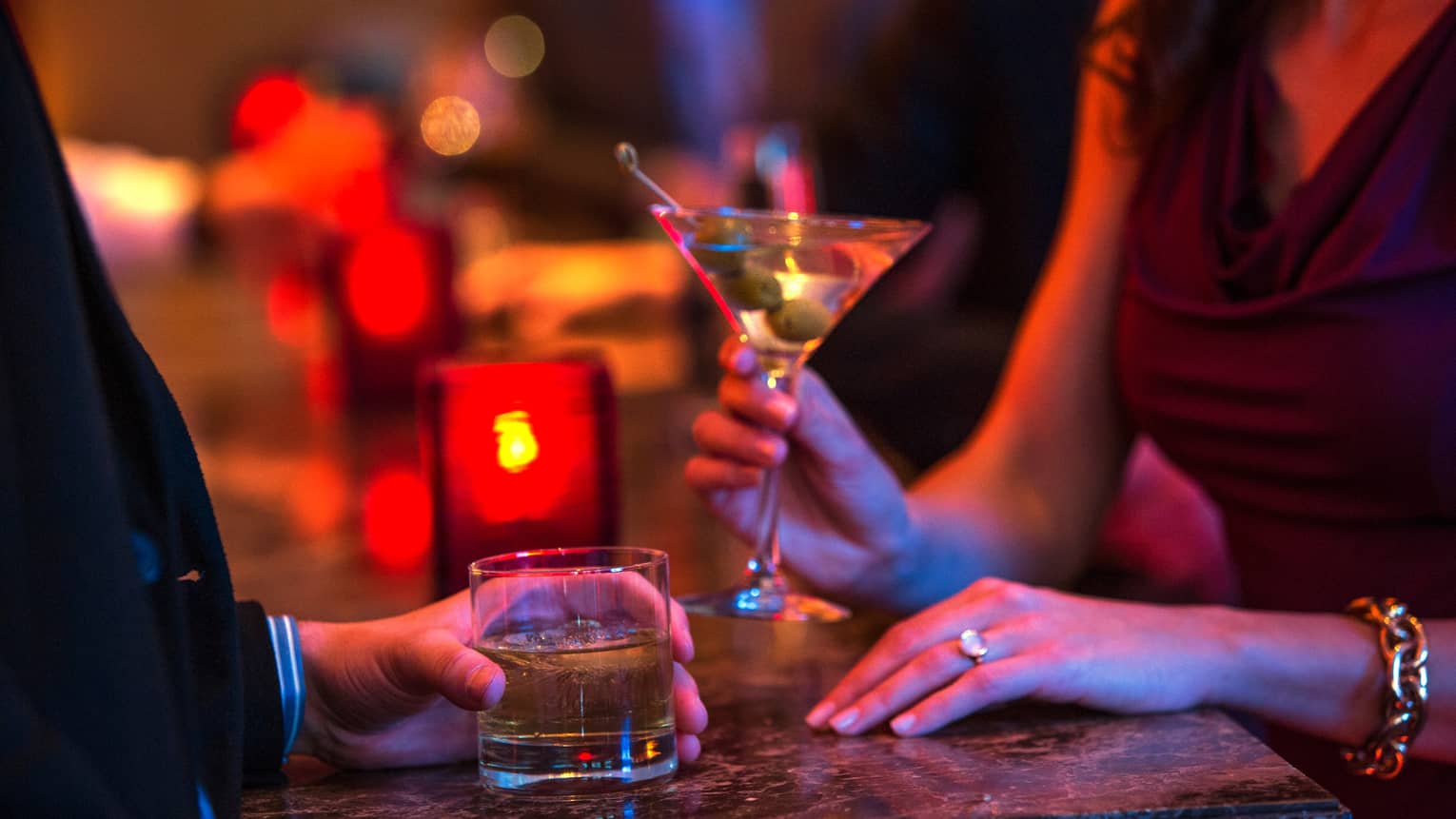 Ty Bar close-up of man and woman holding cocktails in rock and martini glasses, red candle